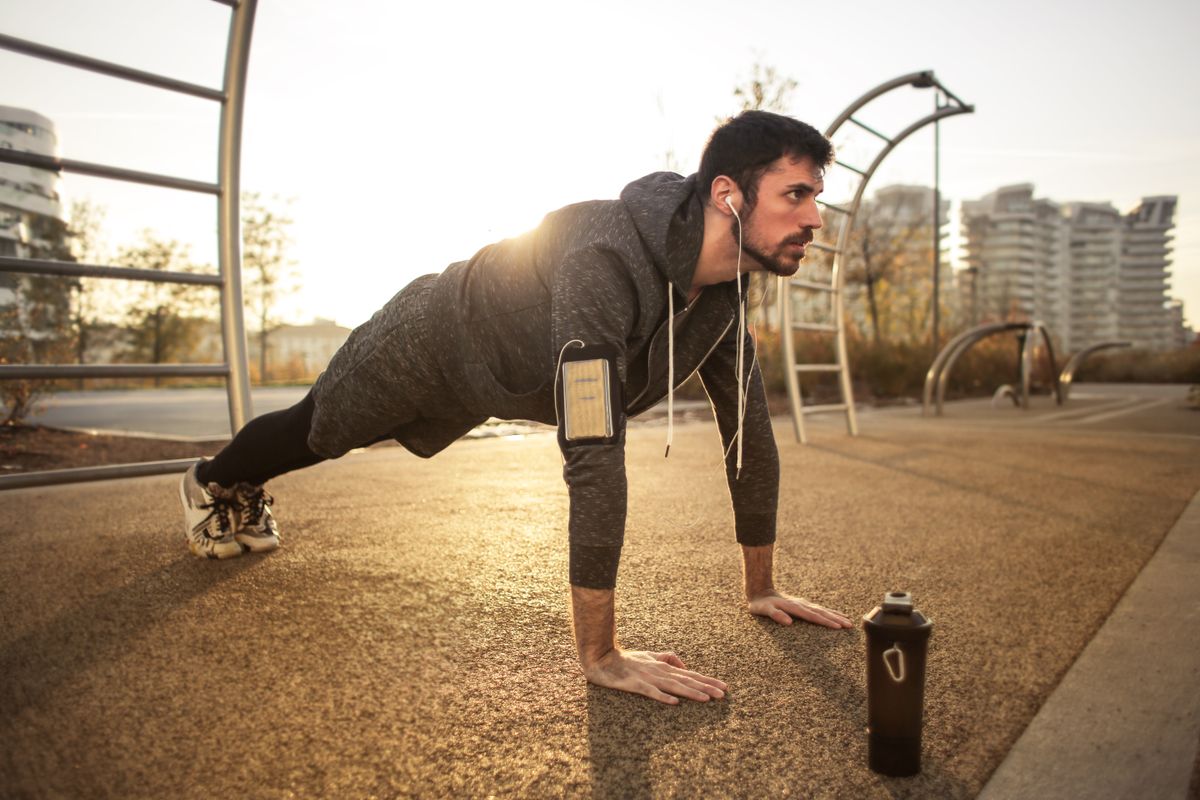 A man doing push-ups outdoors at sunrise